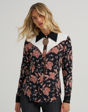 Long-sleeve black floral shirt with a white yoke, pink flowers, and a western-style collar. Features a bolo tie and button detailing.