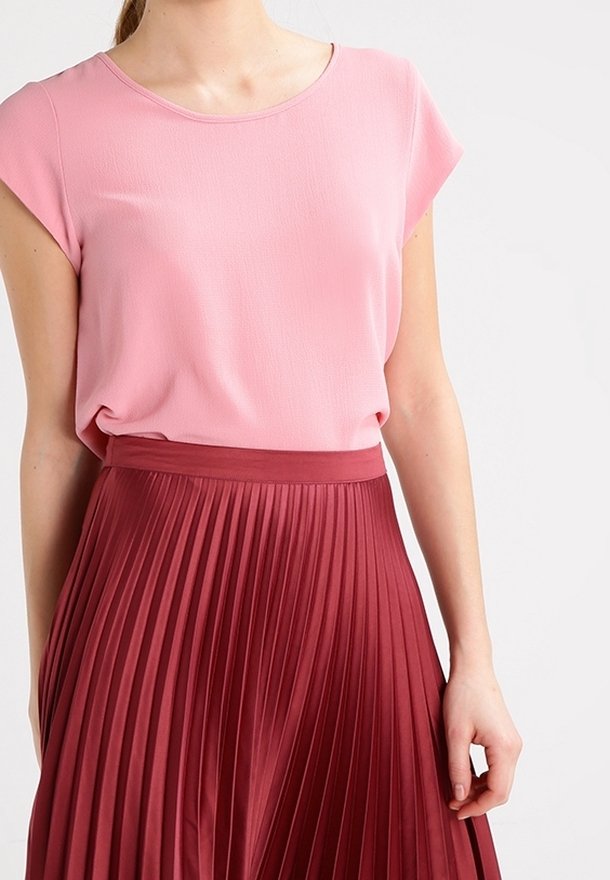Un haut rose à manches courtes associé à une jupe plissée bordeaux. La jupe présente des plis verticaux et une texture lisse, mettant en valeur son mouvement.
