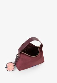 Bordeaux stoffen handtas met een gouden rits, bovenhandvat en een afneembare roze bloemen sleutelhanger. Open interieur.