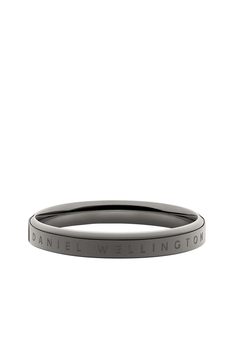 Melnā nerūsējošā tērauda aproce ar gludu, noapaļotu formu; vienā pusē ir iegravēts teksts "DANIEL WELLINGTON".