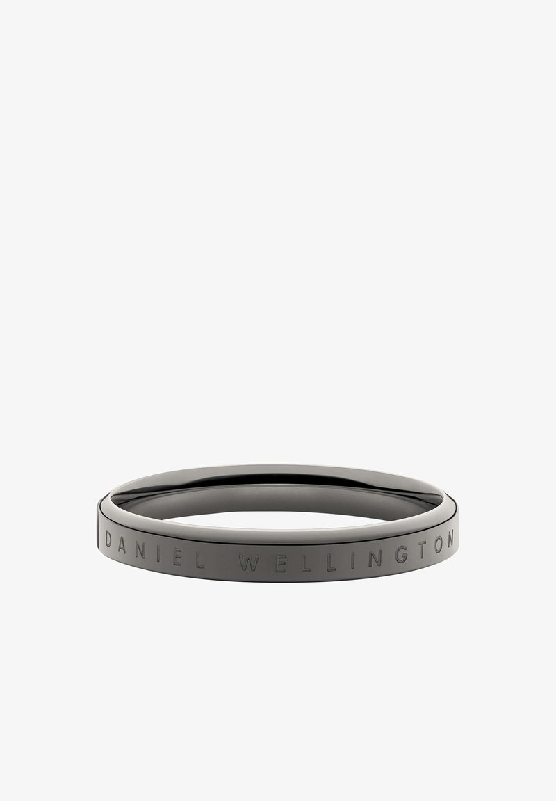 Svart stainless steel bangle med en slät, rund form; har graverad "DANIEL WELLINGTON" text längs ena sidan.