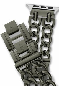 Pulsera de metal con grandes eslabones de cadena brillantes en gris oscuro. La hebilla tiene forma rectangular con el nombre de la marca "GUESS" grabado.