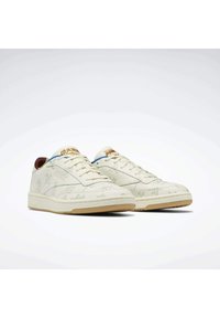 Baskets en cuir blanc avec un motif texturé, une languette bleue et des accents dorés sur les lacets. Elles présentent une semelle beige clair pour un contraste supplémentaire.