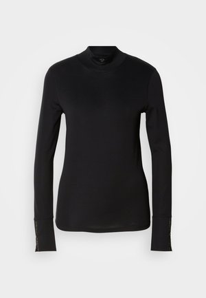 Black long-sleeve turtleneck shirt with a fitted design, soft texture, and gold-tone accent at the cuffs and logo detail near the hem.