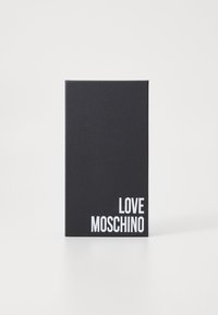 Caderno retangular preto com capa texturizada, apresentando "LOVE MOSCHINO" em fonte branca em negrito no canto inferior direito.
