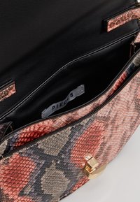 Borsa con un design a stampa rettile testo in rosa e grigio, dotata di chiusura a scatto dorata e fodera interna nera. Etichetta del marchio visibile all'interno.