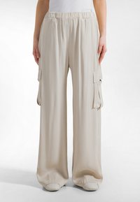 Lichtbeige wijde cargo broeken met een elastische tailleband, voorzien van twee zijzakken en een gladde, zachte stoftextuur.