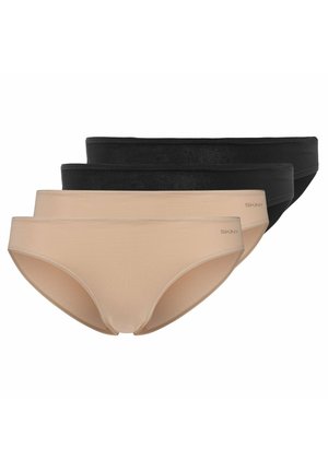Donna dalla pelle chiara che indossa un reggiseno nero e biancheria intima nera abbinata, in piedi su uno sfondo bianco.