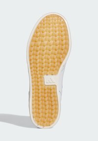 Vit sneakersula med en texturerad gummiyta i ett cirkulärt mönster, kompletterad med en beige mellansula och en gummidetalj vid hälen.