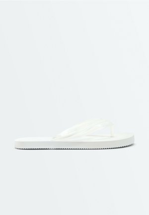 Une seule sandale blanche de type tongs avec une semelle texturée et des brides tressées, vue de profil sur un fond uni.