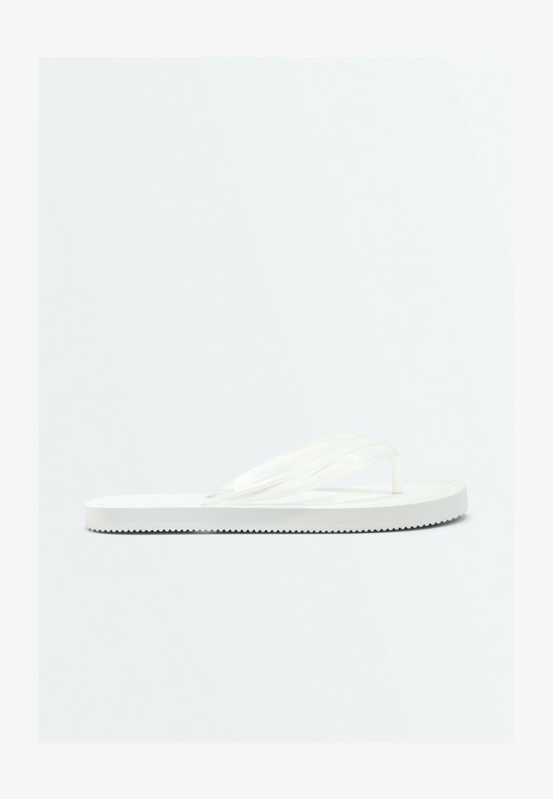 Une seule sandale blanche de type tongs avec une semelle texturée et des brides tressées, vue de profil sur un fond uni.