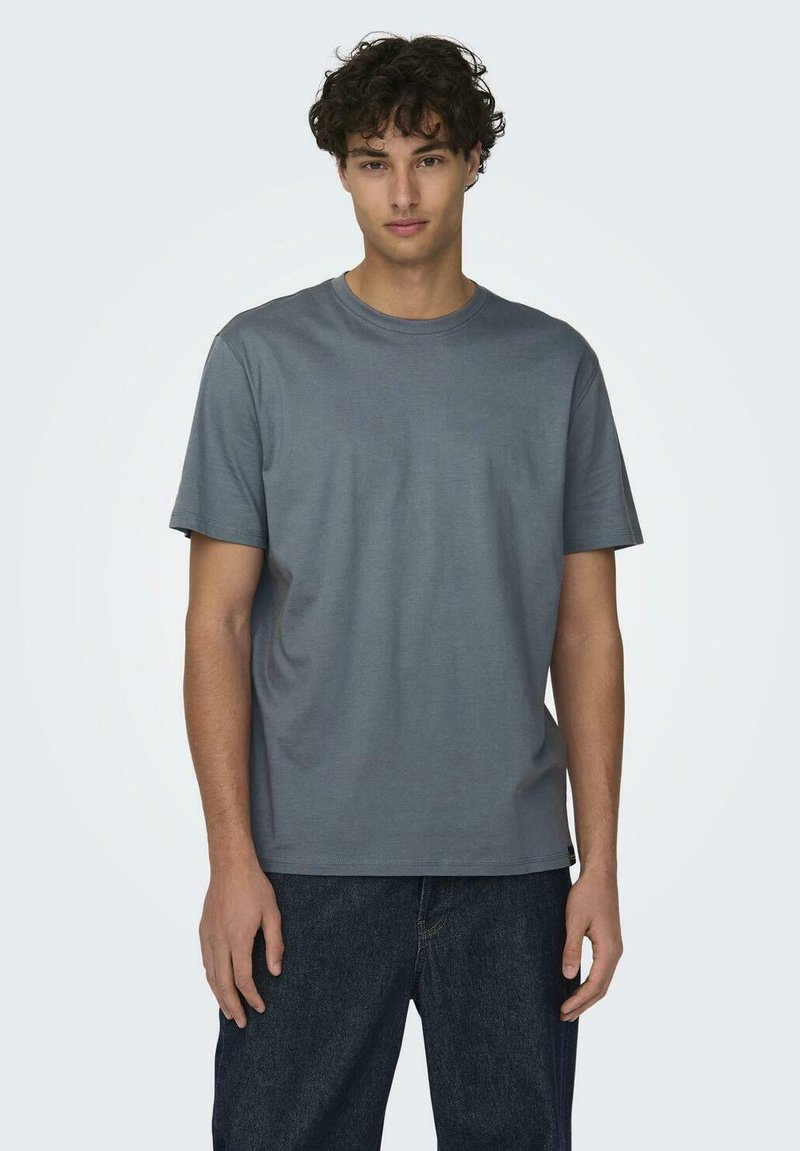 Graues Baumwoll-T-Shirt mit kurzen Ärmeln und Rundhalsausschnitt, mit glatter Textur und geradem Schnitt, kombiniert mit dunkler Jeans.