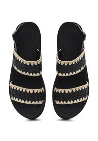 Sandales noires avec texture tressée, dotées de deux sangles tressées accentuées de détails beiges et d'une boucle pour le réglage. Semelles plates.