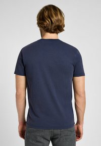 Camiseta de cuello redondo azul marino hecha de algodón. Mangas cortas, corte regular, textura suave, diseño minimalista sin patrones ni acentos visibles.