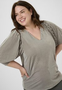Haut gris clair avec des plis verticaux, en V, et des manches courtes évasées. Texture lisse et coupe décontractée. Design minimaliste avec des accents subtils.