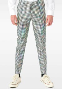 Pantalones con patrón holográfico y diseño ajustado, que presentan una cuadrícula de cuadros reflectantes en varios colores, combinados con zapatillas blancas.