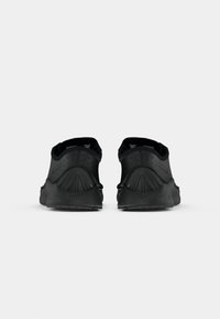 Pantofi sport negri cu un superior texturat, design cu toc rotund și accent proeminent al tocului. Include decupaje pentru respirabilitate și talpă cu aderență.