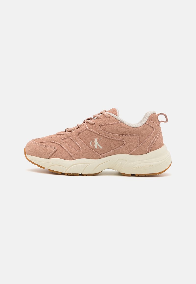 Baskets en daim rose clair avec semelle blanche coussinée, laçage à l'avant et un petit logo "cK" sur le côté.