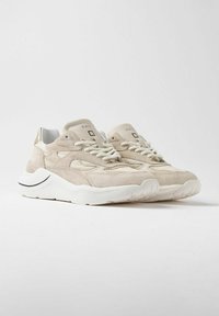 Sneaker in suede beige con suole bianche, dotate di pannelli testurizzati, design con lacci e branding minimale sulla linguetta.