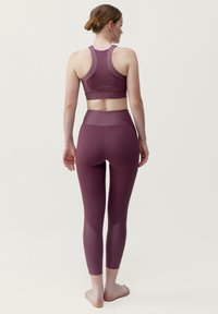 Mauve sportbehå och leggings-set tillverkat av mjukt, elastiskt tyg. Behån har en racerback-design och leggingsen har en hög midja.
