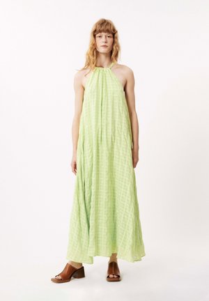 Hellgrünes Neckholderkleid aus leichtem Stoff mit einem Karomuster. Das Model trägt braune, hohe Sandalen. Einfaches, fließendes Design.