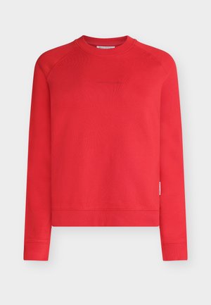 Punainen pitkähihainen pusero pyöreällä pääntiellä, jossa on resorireunukset hihoissa ja helmassa, hienovarainen brändin logo rintakehässä, valmistettu pehmeästä kankaasta.