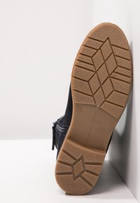 Svart mockastövel med gummisula, med ett texturerat mönster på sulan. Dragkedjedetalj på sidan. Storlek 37 märkt på sulan.