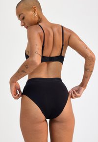 Set di lingerie nera con design semplice, spalline regolabili e una fascia larga con il nome del marchio. Tessuto liscio ed elastico.
