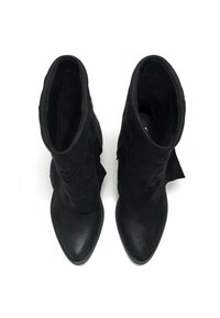 Botas de tobillo negras con punta de piel suave y parte superior texturizada. Presentan un diseño con doblez y punta afilada, con detalles de costura.
