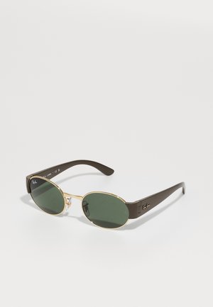 Silmät ovalihkaiset vihreät linssit, ohut kultainen metallirunko ja paksut tummanruskeat templat, Ray-Ban-logo linssissä ja templassa.