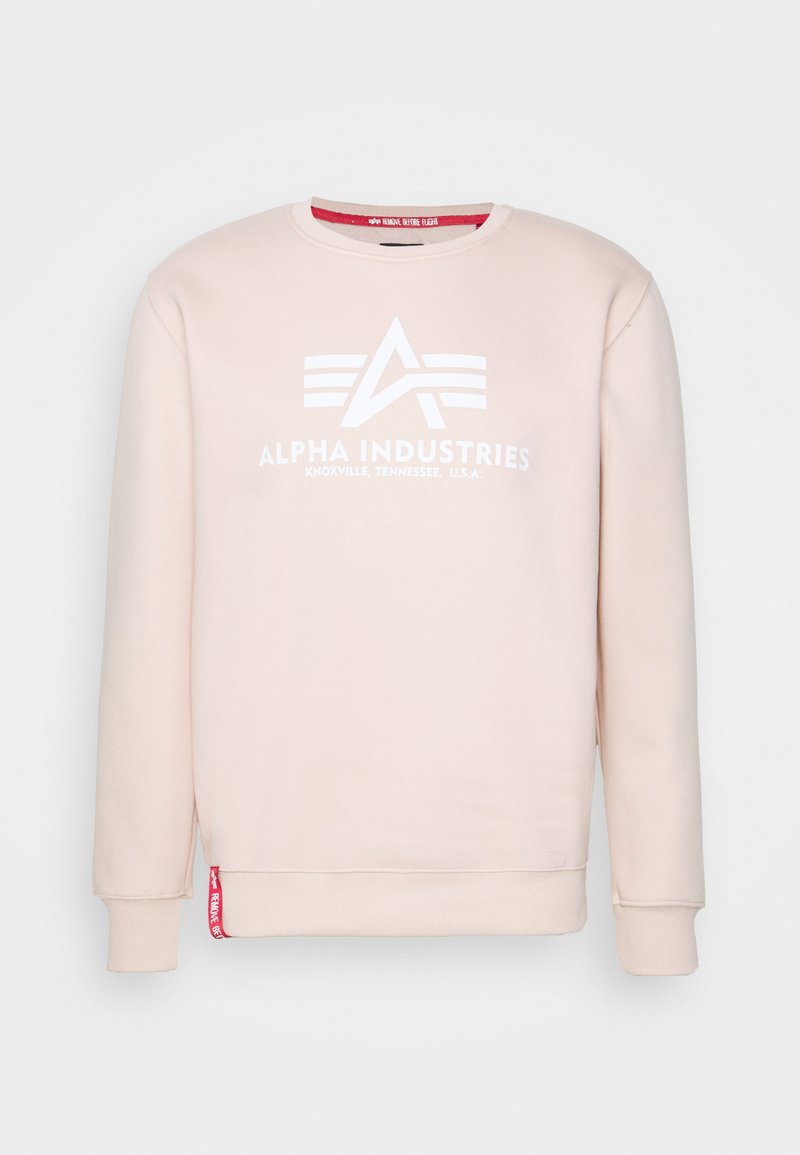 Sudadera de color rosa claro hecha de tejido suave, con un logo blanco que presenta una "A" estilizada y rayas en el pecho. Los puños y el dobladillo son de canalé.