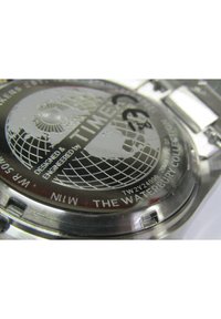Orologio in acciaio inossidabile con quadrante nero inciso che presenta un design a globo, grado di impermeabilità e dettagli argentati.