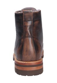 Bottines en cuir marron avec une surface lisse, un bout rond, un talon renforcé et une semelle superposée contrastante avec un bord marron clair.