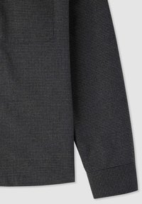 Tessuto di camicia a quadri grigia con tasca quadrata e polsino, con una finitura testurizzata a motivo a griglia.