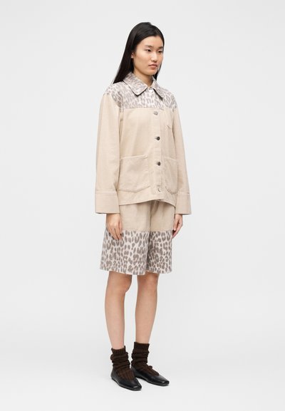 Μπεζ σακάκι με λεοπάρ ώμους και δύο μπροστινές τσέπες, σε συνδυασμό με σορτς που έχουν το ίδιο λεοπάρ μοτίβο στα τελειώματα.