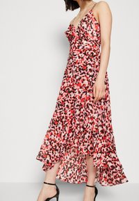 Blommig maxiklänning med en volangkrage, justerbara axelband, i nyanser av röd, svart och rosa; lättviktsmaterial med en svängande fåll.