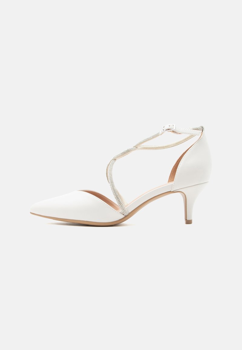 Chaussure blanche à talon moyen et bout pointu avec des brides croisées ornées de strass et une boucle à la cheville sur un fond clair.