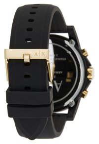Bracelet de montre en caoutchouc noir avec boucle dorée, portant les initiales de la marque. Cadran de montre rond avec un fond noir et des accents dorés, design résistant à l'eau.