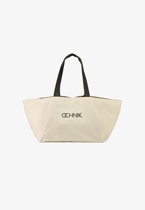 Beżowa torba na ramię z płótna z czarnymi uchwytami, z delikatnym fałdem na górze, z nadrukowanym na czarno słowem "OCHNIK".