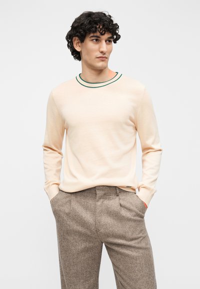 Beež pikkade varrukatega kudumriietus rohelistest ja mustadest triipudest kaelusega, pruuni tekstuuriga pükstega, küljetaskutega.