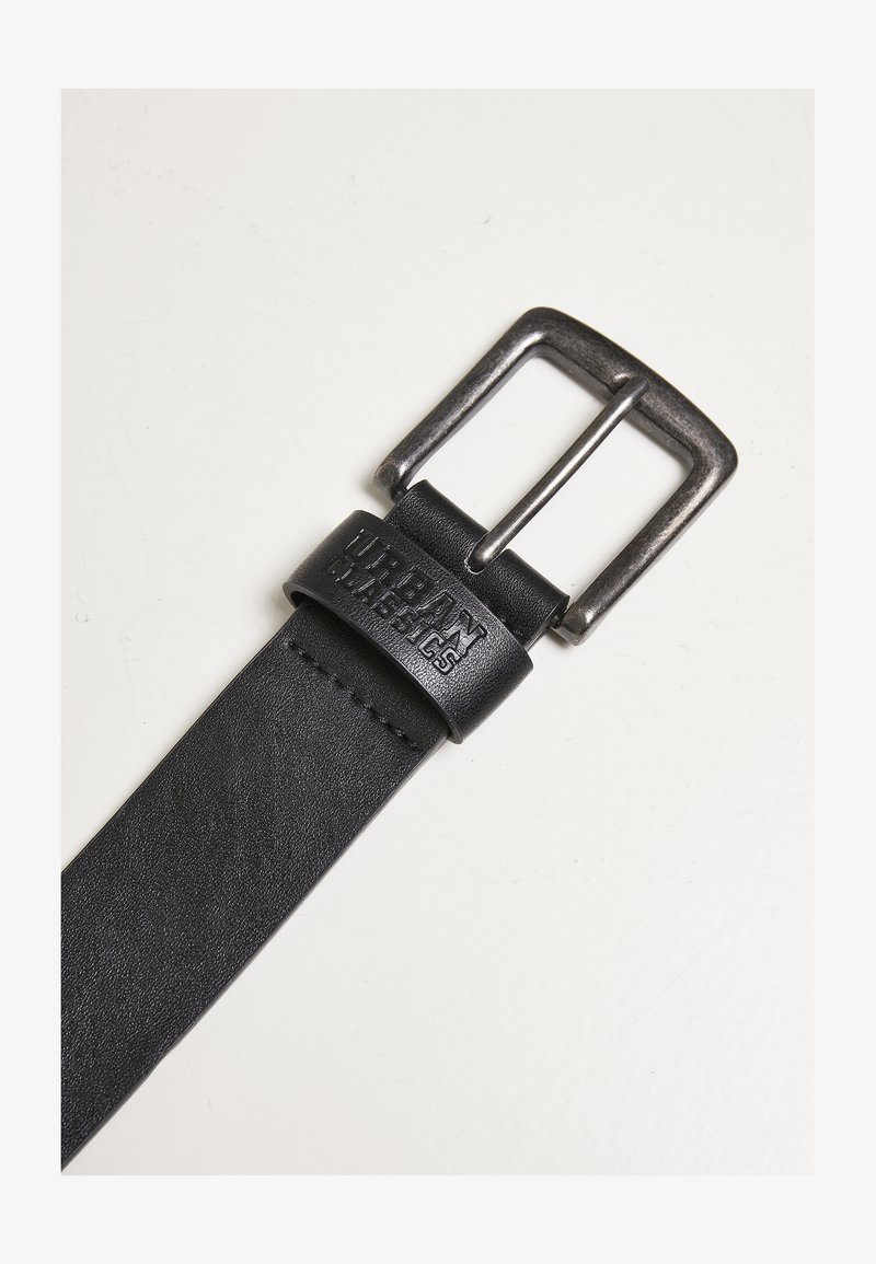 Schwarzer Leder Gürtel mit einer Metall-Schnalle mit gebürsteter Oberfläche. Der Riemen hat eine strukturierte Oberfläche und ein geprägtes Logo.