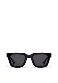 Mustad mustad päikeseprillid paksude raamidega ja tumedate läätsedega, esiplaanil valgel taustal.