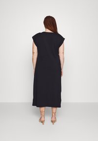 Černé maxi šaty bez rukávů se volným střihem a kulatým výstřihem, které mají hladkou texturu a délku do poloviny lýtek.