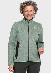 Grüne, strukturierte Fleecejacke mit hohem Kragen, kompletter Reißverschluss und schwarzen Reißverschlusstaschen. Mit einem Logo auf der linken Brust.