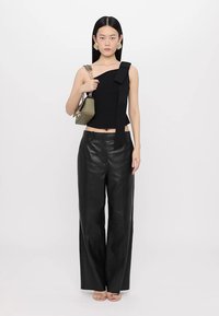 Must have mustrindiga musta tank top ühte õlga katva disainiga ja kaarikoes detailiga, koos laia jala mustade nahkpükstega ja väikese rohelise käekotiga.