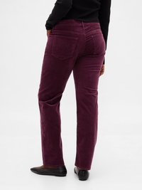 Pantalon en velours côtelé bordeaux avec jambe droite, deux poches arrière et surface texturée. Associé à des ballerines noires.