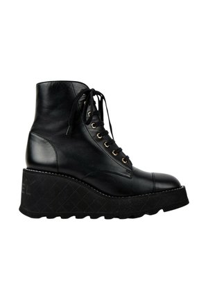 Bottine noire en cuir à lacets montant à la cheville avec semelle compensée épaisse et semelle rainurée, vue de profil sur fond blanc.