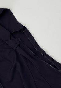 Granatowa zapinana odzież z miękkiego materiału, o eleganckim designie, z zapięciem na zamek błyskawiczny z przodu, charakteryzująca się gładką teksturą.