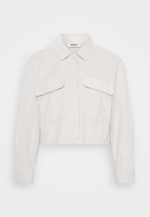 Cropped light beige jacket with a collared neck, long sleeves, two chest pockets, and a textured fabric finish.