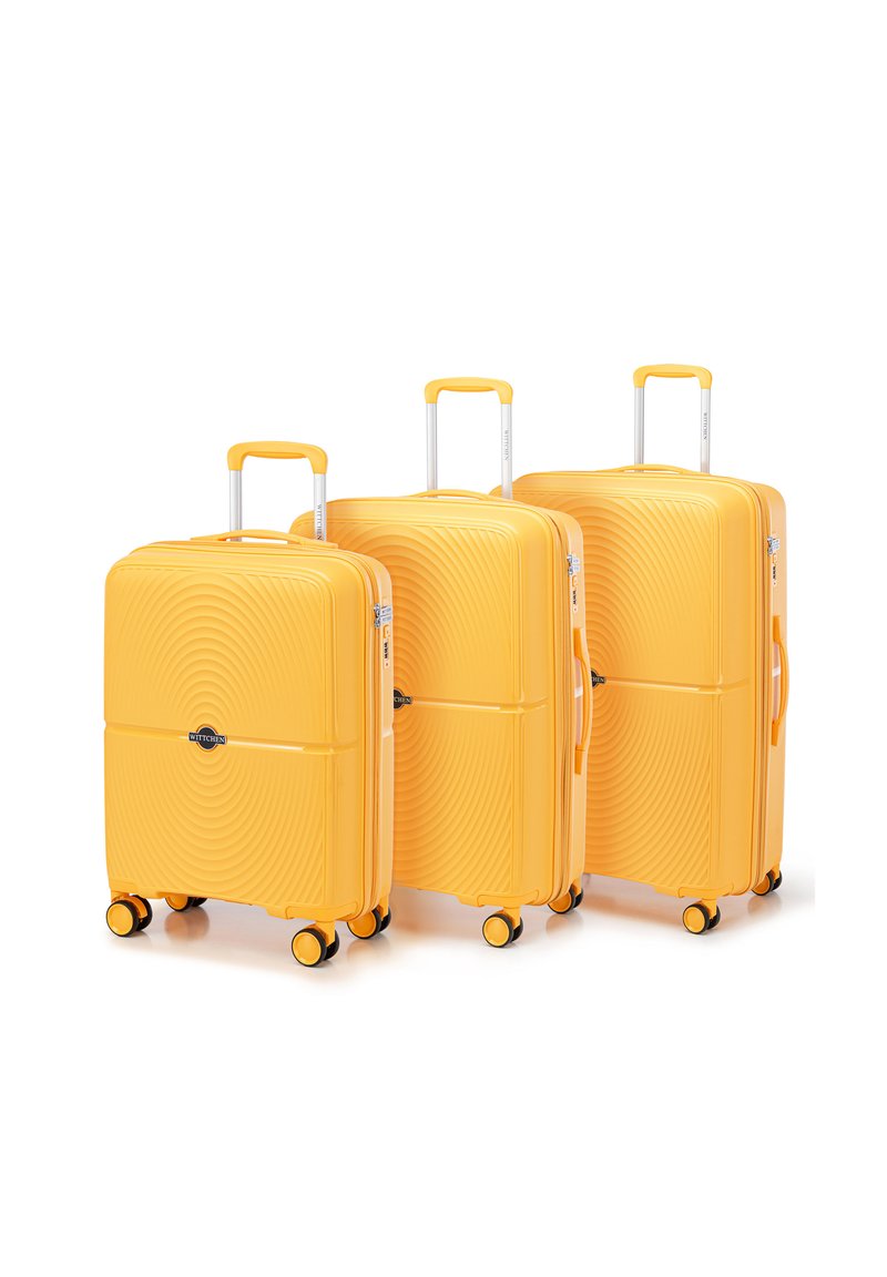 Set di tre valigie gialle rigide con motivi a onde in rilievo, manici telescopici e quattro ruote multidirezionali.
